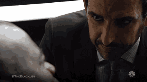 a man in a suit and tie is looking at another man with #theblacklist on the bottom