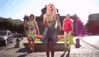 a woman with pink hair is standing in front of two other women