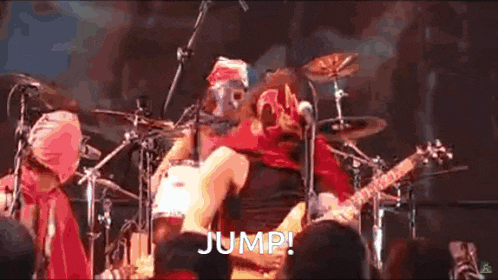 a man in a mask is playing a guitar on a stage in front of a microphone .