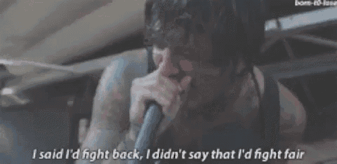 a man with tattoos is singing into a microphone and says i said i 'd fight back