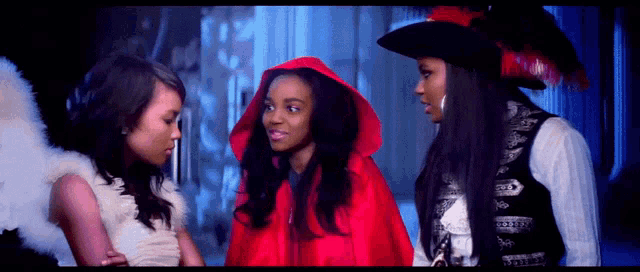 a woman in a red cape is standing next to two other women