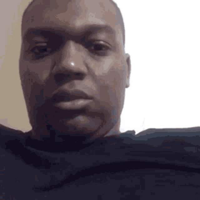 a man in a black shirt is taking a selfie with a white background .