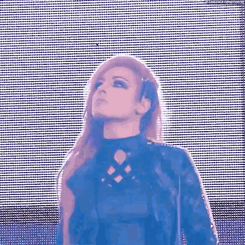 a woman in a black jacket is standing in front of a blue and white screen .