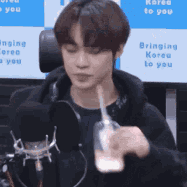 a young man is sitting in front of a microphone holding a bottle of milk .