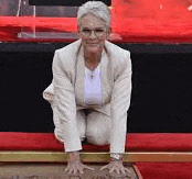 a woman in a white suit is kneeling down on a red carpet with her hands on a plaque .