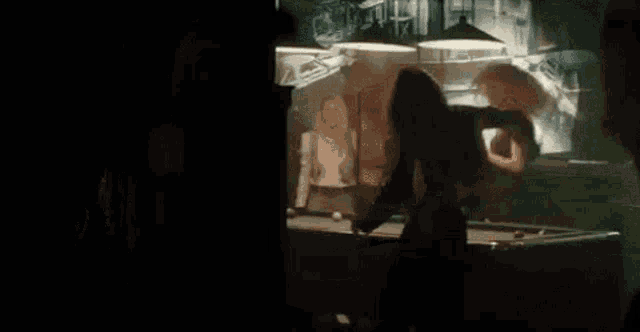 a woman is standing in front of a pool table in a pool hall .