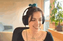 a woman wearing headphones is smiling while sitting in a chair in front of a window .