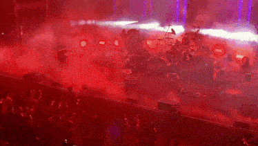a group of people are playing instruments on a stage with red smoke coming out of it