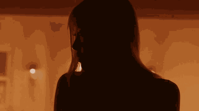a silhouette of a woman with long hair looking down