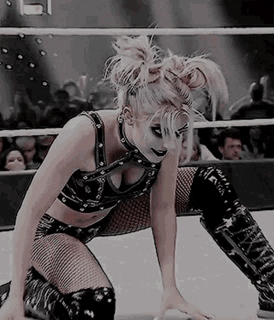 a woman is kneeling down in a wrestling ring with her legs crossed .