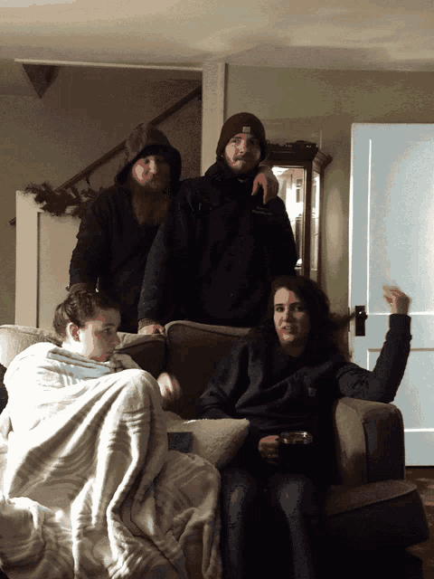 a group of people are sitting on a couch and one of them is wearing a black hoodie