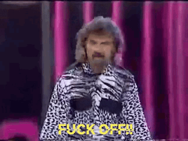 a man in a zebra print shirt is standing in front of a pink curtain and saying fuck off .