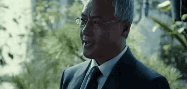 a man in a suit and tie is wearing glasses and earbuds .