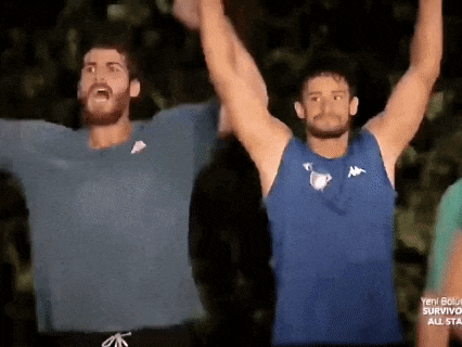 two men are standing next to each other with their arms raised in the air .