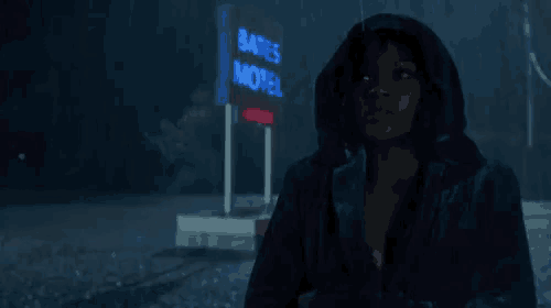 a woman is standing in front of a motel sign at night .
