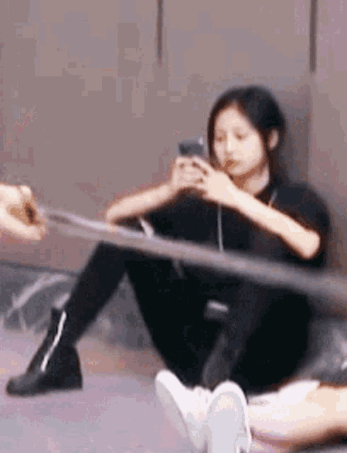 a woman is sitting on the floor with her legs crossed and looking at her phone .