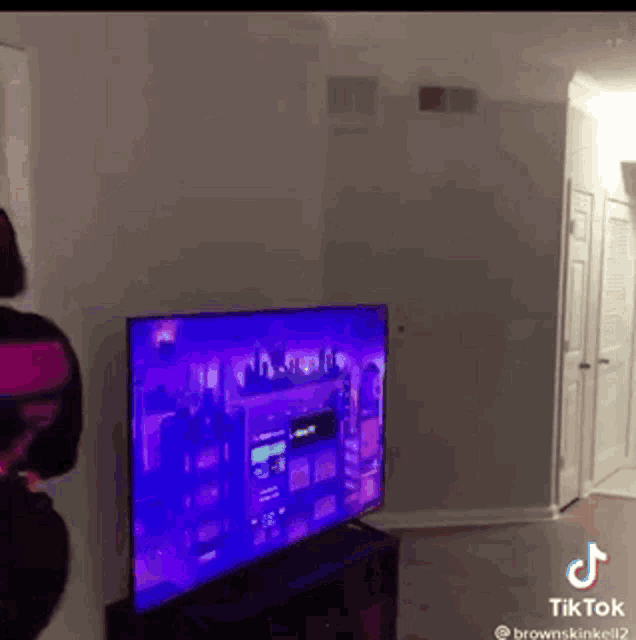 a woman is standing in front of a tv with a purple screen