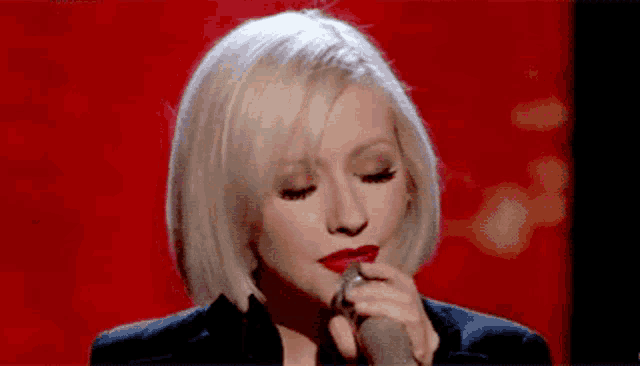 a woman singing into a microphone with red lipstick on her lips
