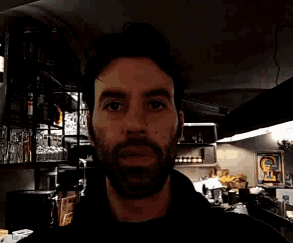 a man with a beard looks at the camera in a restaurant