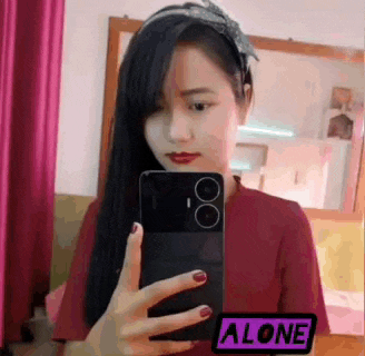 a woman is taking a selfie in front of a mirror with her phone .