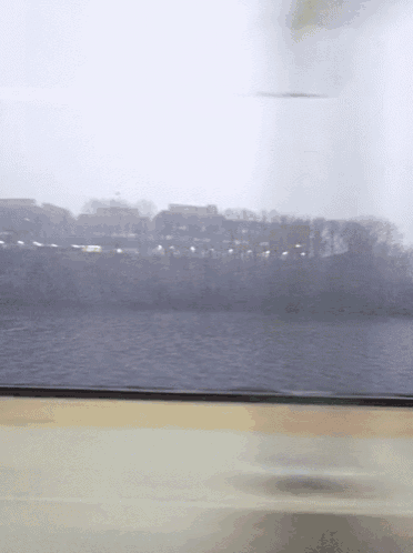 a blurred image of a body of water with buildings in the distance