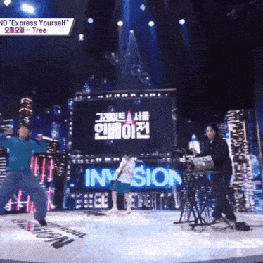 a group of people are dancing on a stage with a large screen behind them that says " express yourself "