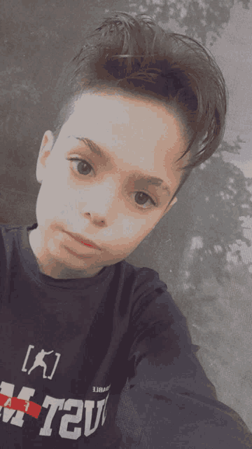 a young boy taking a selfie wearing a t-shirt that says " k "