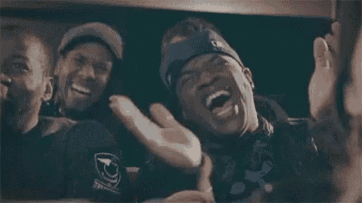 a group of men are sitting next to each other in a car and laughing .