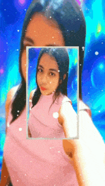 a woman in a pink top is taking a selfie with a blue background