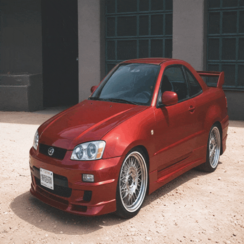 a red car with a license plate that says atlanta on it is parked in the dirt