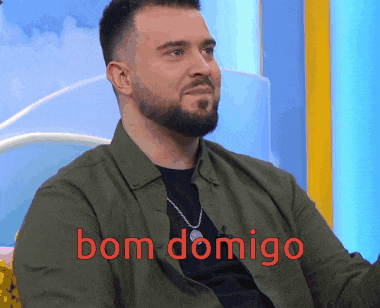 a man with a beard is sitting in front of a sign that says bom domigo