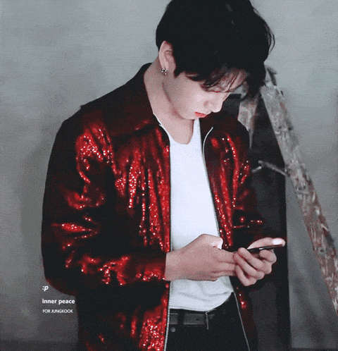 a young man in a red jacket looks at his phone
