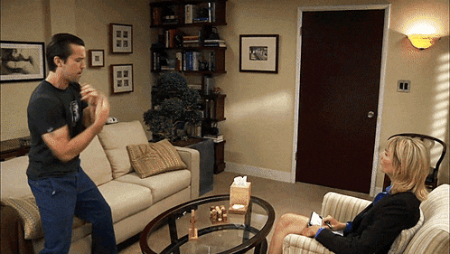 a man is standing in front of a woman sitting in a chair in a living room