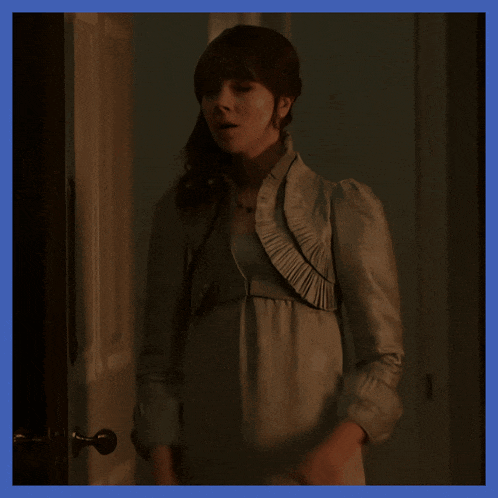 a woman with her arms crossed is standing in a dark room