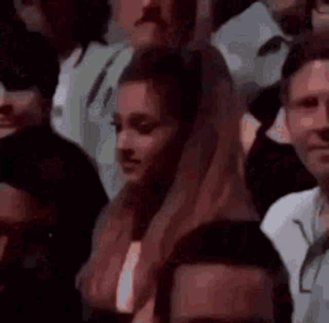a woman is sitting in a crowd of people and looking at the camera .