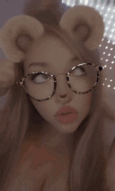 a woman wearing glasses and bear ears looks up at the camera