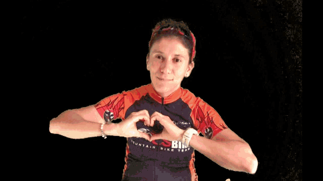 a woman making a heart with her hands wearing a shirt that says mountain bike team
