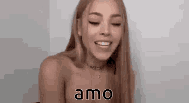 a woman without a shirt is smiling with her eyes closed and the word amo is on her chest .
