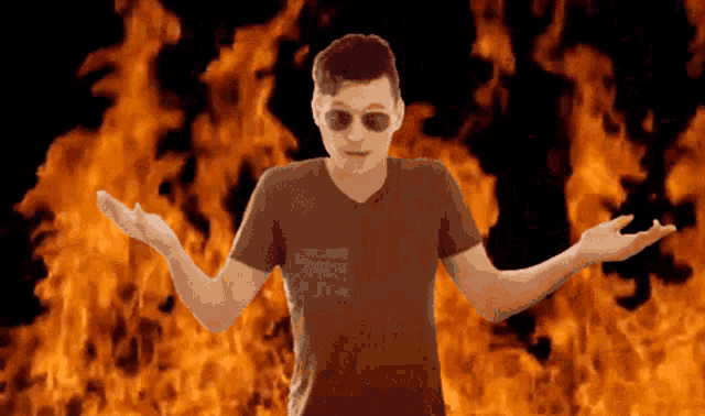 a man wearing sunglasses is standing in front of a fire background