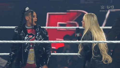 two women are standing in a wrestling ring with a usa logo on the bottom