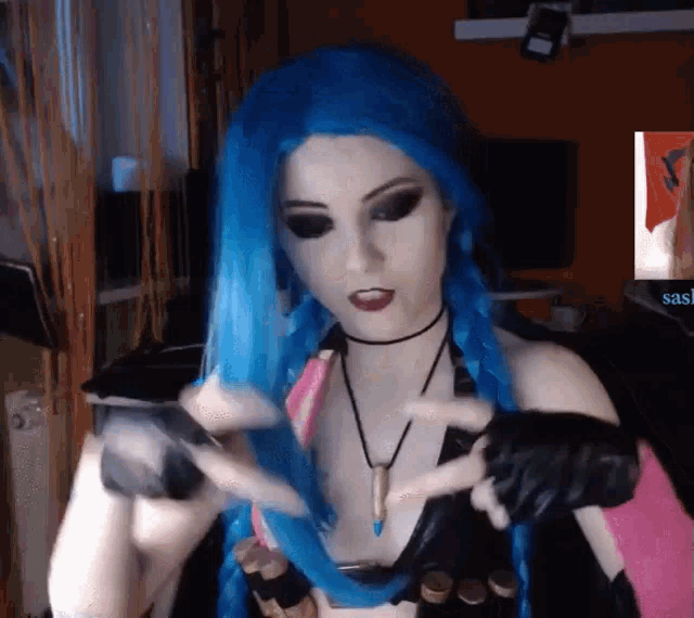 a woman wearing a blue wig and black gloves holds a bottle