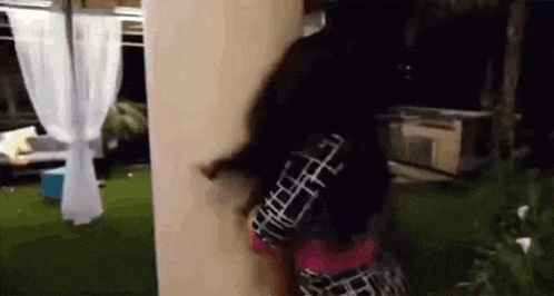 a woman in a plaid shirt is standing next to a wall .