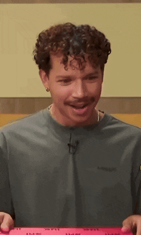 a man with curly hair and a mustache is wearing a grey t-shirt that says carhartt on it