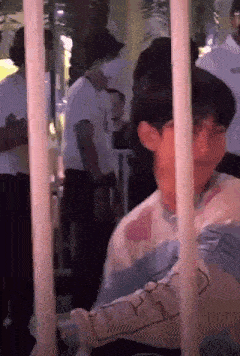 a man is standing in a crowd of people behind bars .