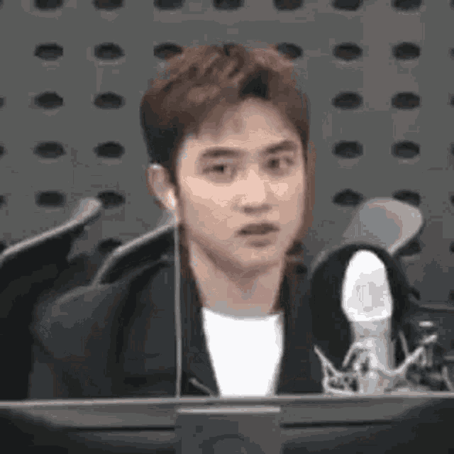 a man wearing headphones is sitting in front of a microphone in a room .