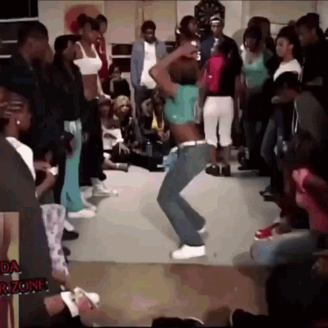 a woman is dancing in front of a crowd in a room with the word zone on the bottom