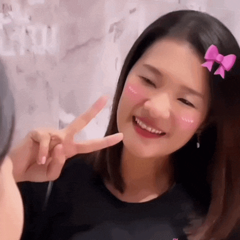 a woman with a pink bow in her hair is smiling and giving a peace sign