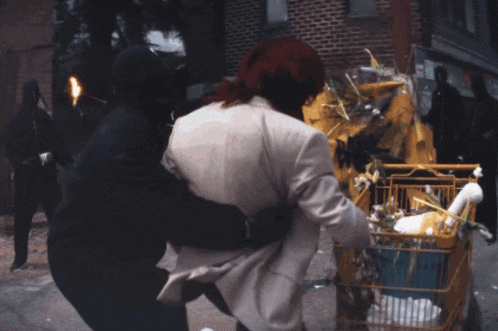 a man is being held by another man in front of a yellow tent that says no