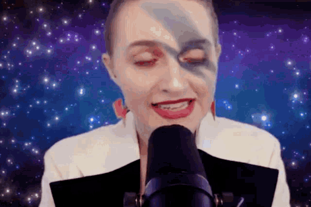 a woman singing into a microphone with a galaxy background
