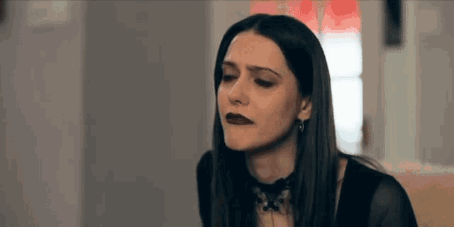 a woman wearing a choker and earrings is making a funny face .